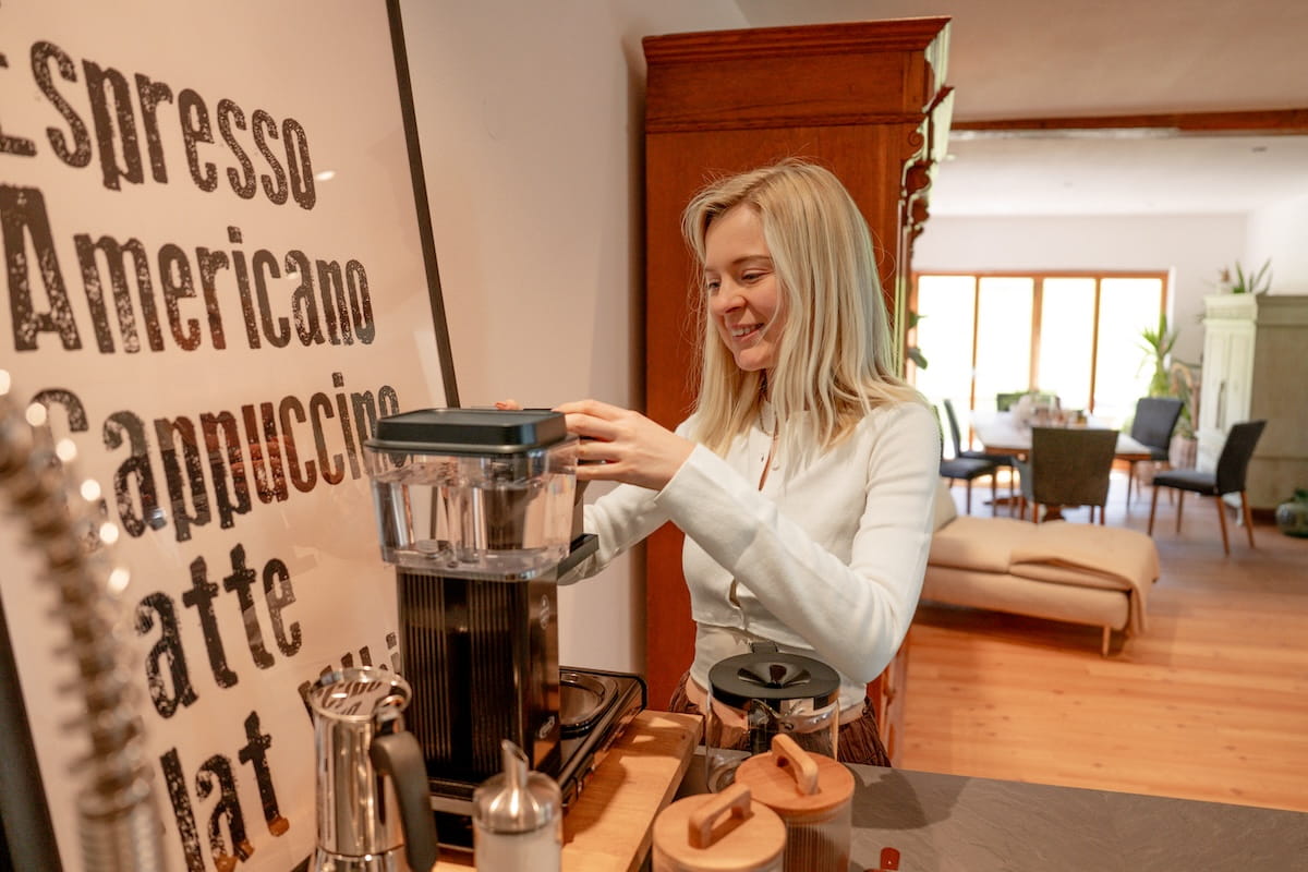 Kaffeestation im Mika Hof mit Kaffeemaschine und offenem Wohnbereich im Hintergrund.