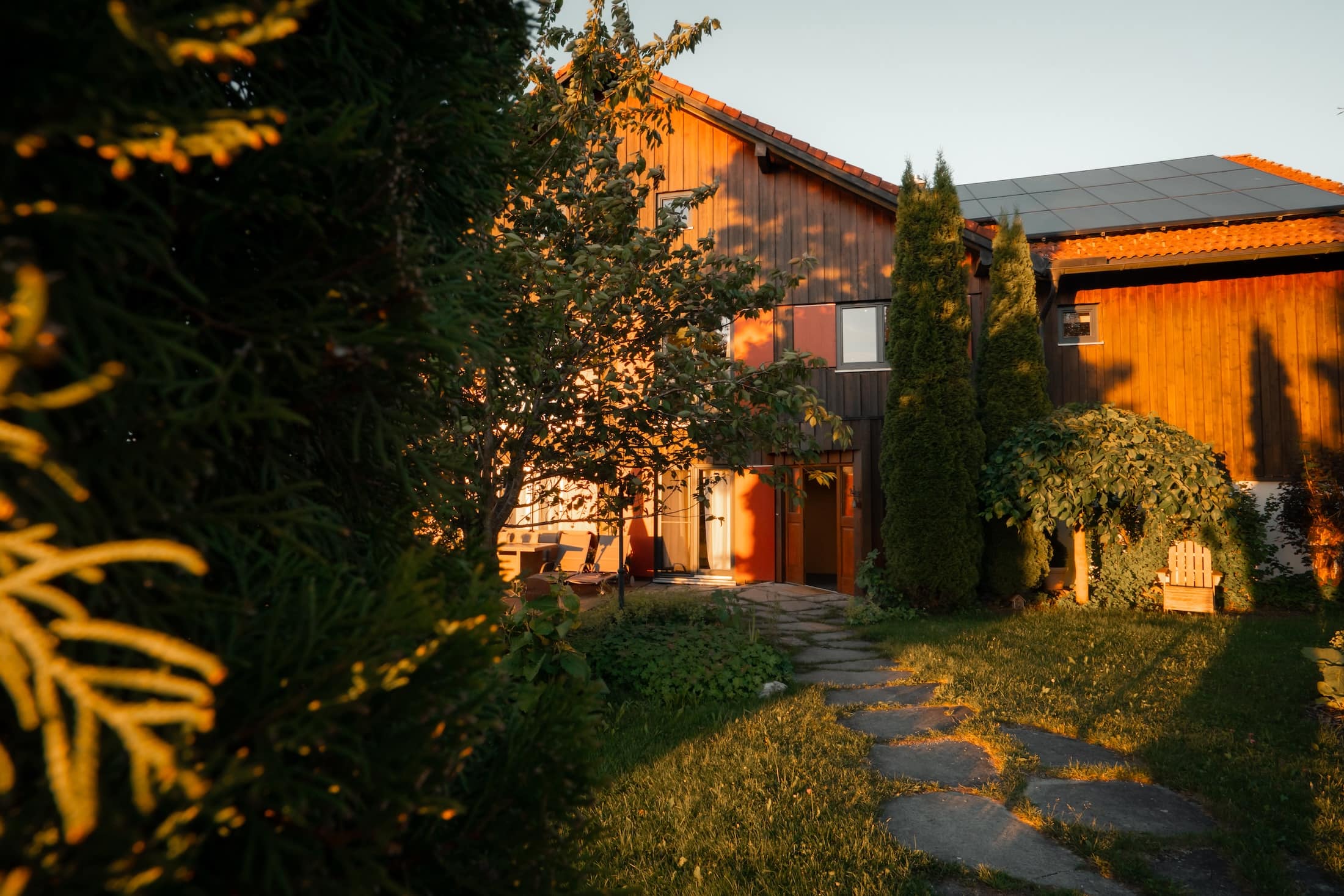 Mika Hof in Weitnau mit Garten und Holzfassade im warmen Licht der Abendsonne