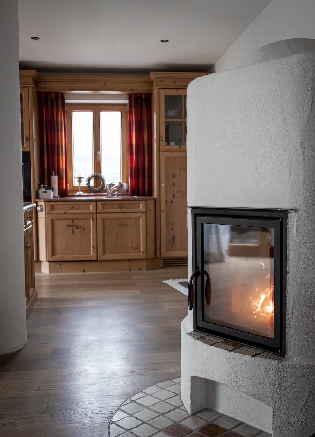Brennender Kamin neben Holzküche in der Ferienwohnung Sonneck am Mika Hof im Allgäu